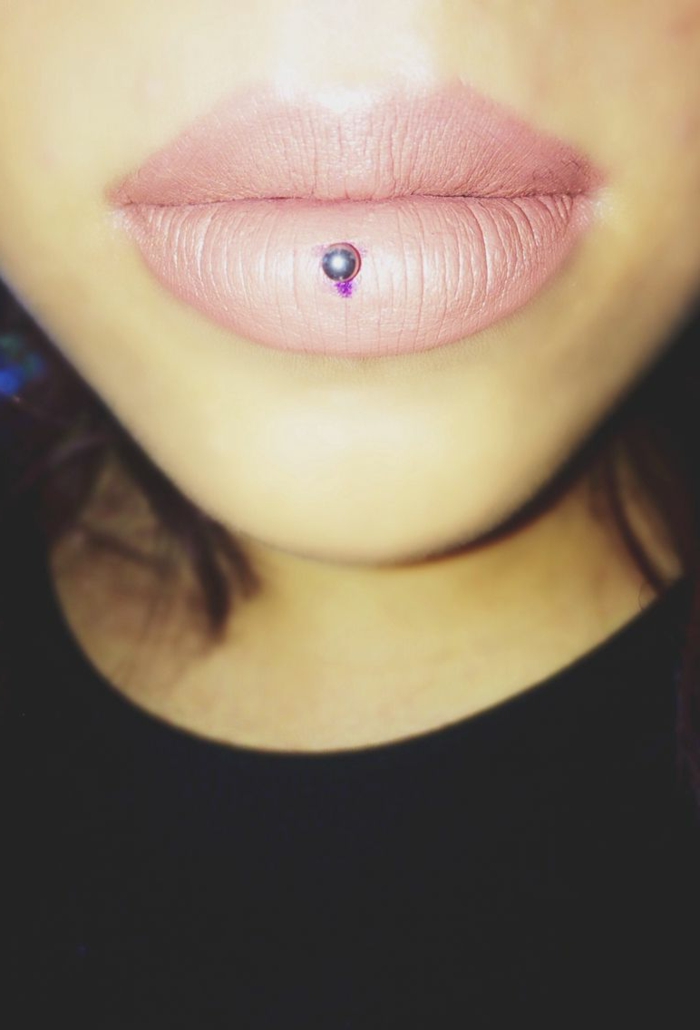 close up photo, lips with pink matte lip gloss, horizontal lip piercing, girl wearing black blouse