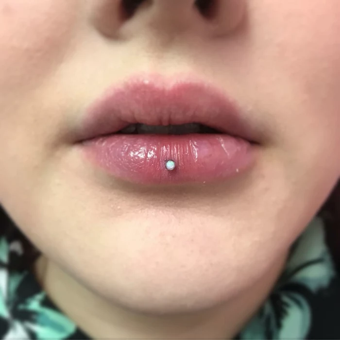 close up photo, lips with clear lip gloss, horizontal lip piercing, white rhinestone