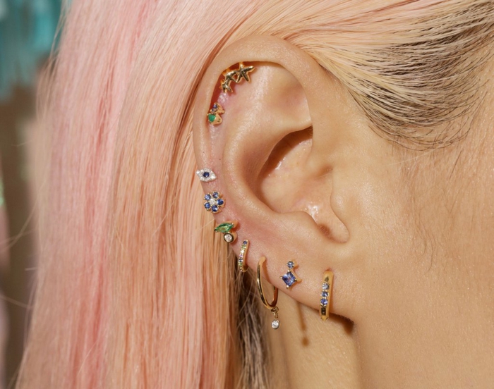 woman with blonde pink hair, wearing multiple different earrings, triple helix piercing, colorful rhinestones