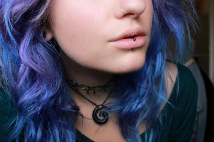 woman with blue and purple hair, labret piercing, nose ring piercing, wearing black blouse