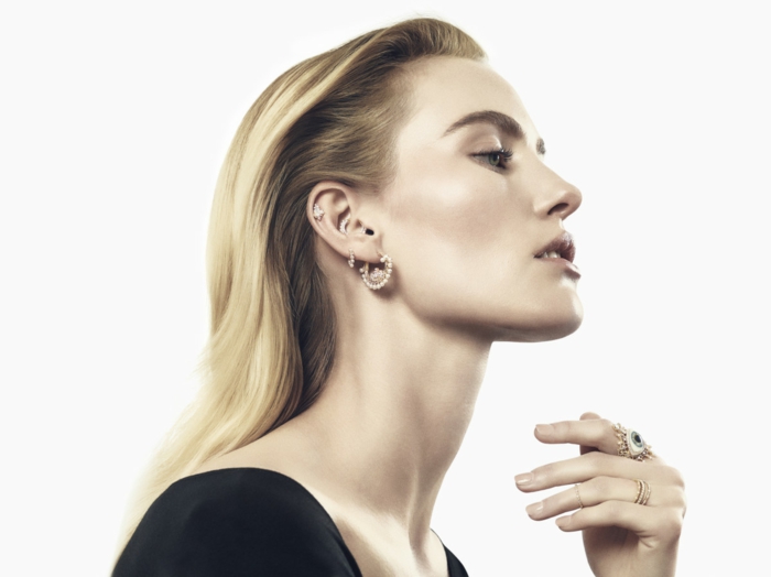 woman with blonde hair, wearing black top, triple helix piercing, multiple earrings with rhinestones