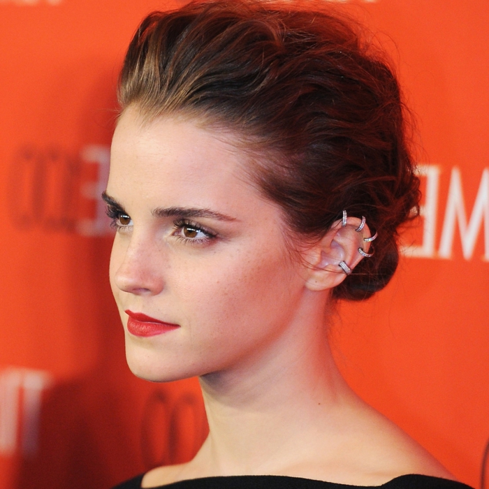 emma watson, brown hair in low updo, helix piercing, red lipstick, multiple ring earrings with rhinestones