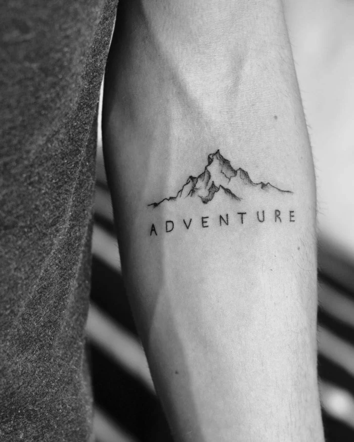 adventure written underneath mountain range, mountain tattoo, forearm tattoo, black and white photo