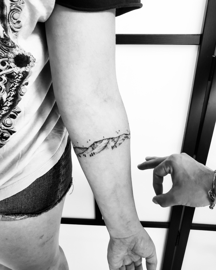 black and white photo, forearm tattoo, small mountain tattoo, mountain range with trees