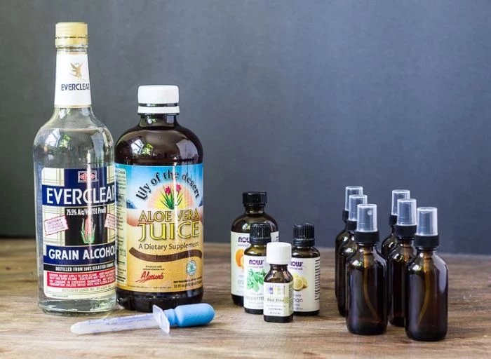 diy hand sanitizer, bottles of grain alcohol and aloe vera juice, small spray bottles of essential oil