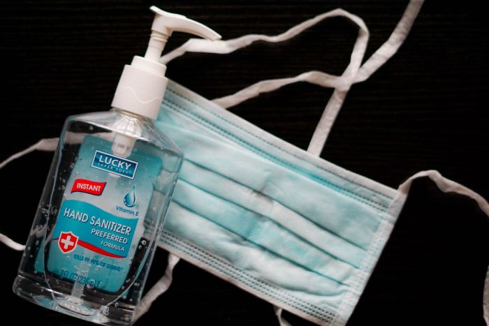 hand sanitizer, plastic bottle of antibacterial gel, surgical face mask, black background