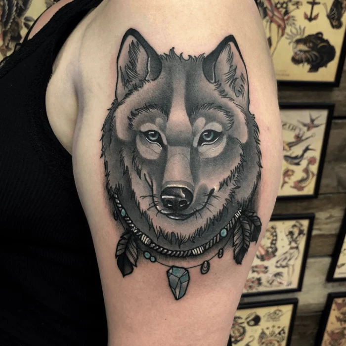 black and grey tattoo, wolf face with necklace with feathers, neo traditional animal tattoo, blue eyes