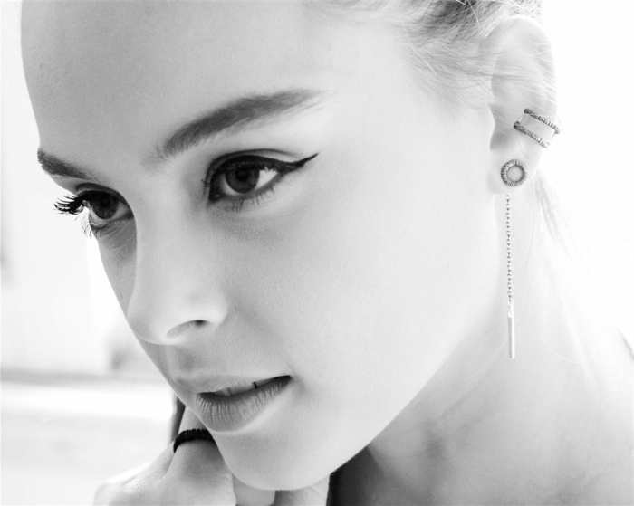 black and white photo, woman with winged eyeliner, cartilage piercing earrings, multiple earrings with rhinestones