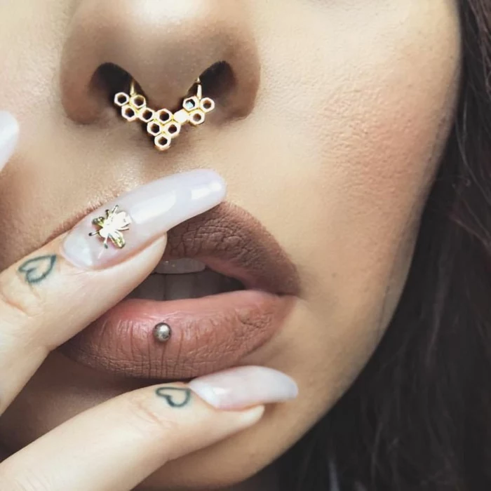 close up photo, woman wearing nude matte lip gloss, ashley lip piercing, honeyvomb septum ring piercing