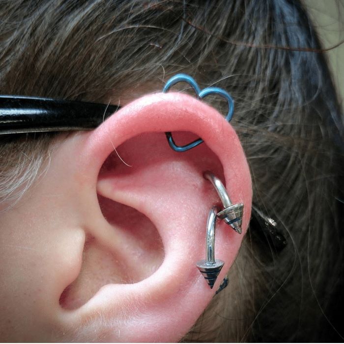 woman with brown hair, wearing multiple earrings, cartilage piercing earrings, close up photo of an ear