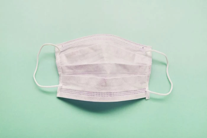 light pink surgical face mask, placed on light blue surface, diy face mask for breathing
