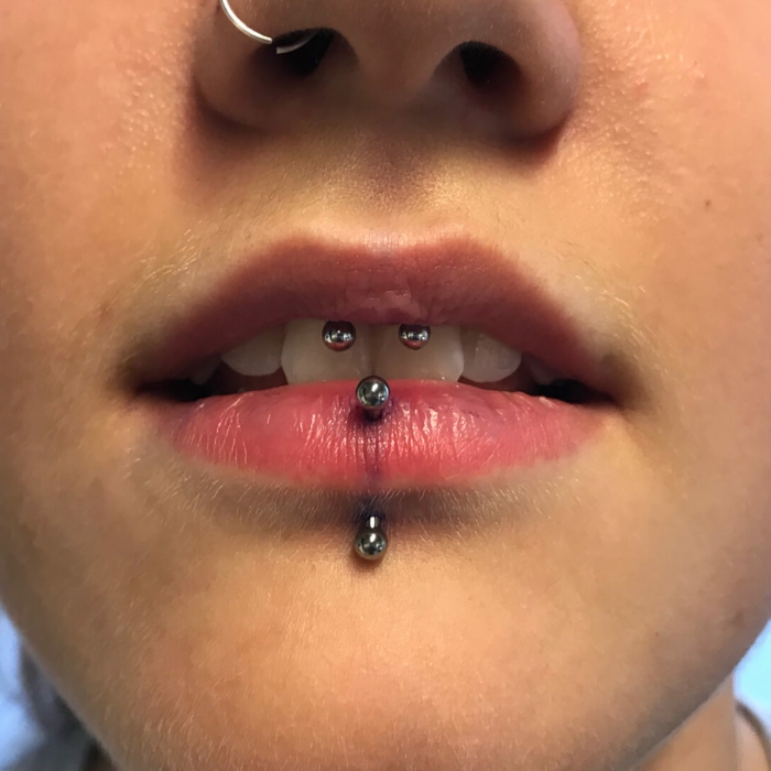 close up photo, different lip piercings, lips with clear lip gloss, nose ring piercing