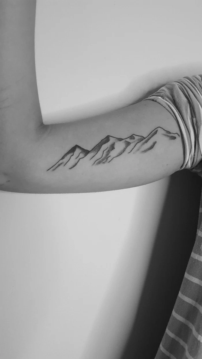 black and white photo, simple mountain tattoo, mountain range on the inside of the arm