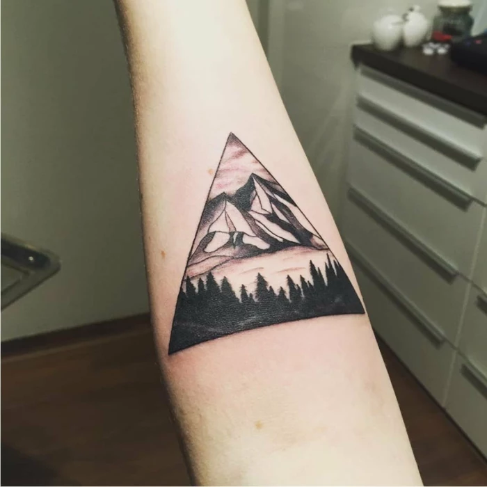 forearm tattoo, minimalist mountain tattoo, mountain range next to lake, surrounded by trees inside a triangle
