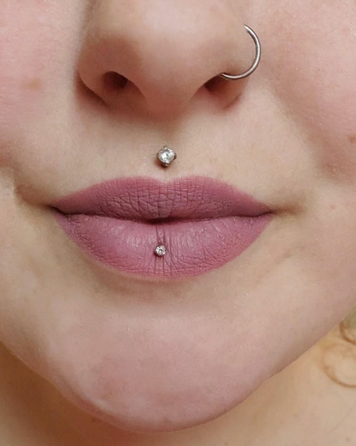 close up photo, lips with pink matte lip gloss, different lip piercings, nose ring piercing