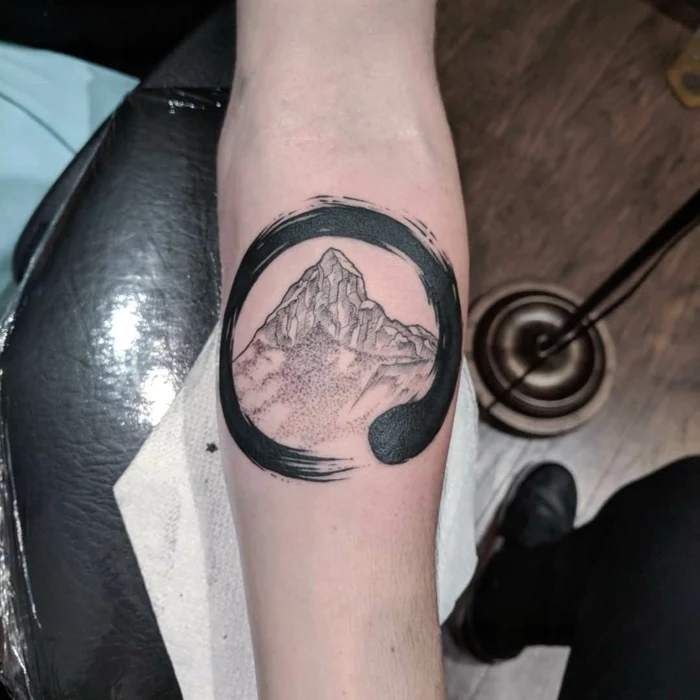 ouroboros symbol around a mountain range, mountain tattoo ideas, forearm tattoo