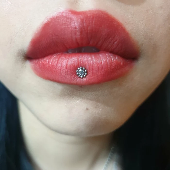 close up photo, lips with red matte lip gloss, labret lip piercing