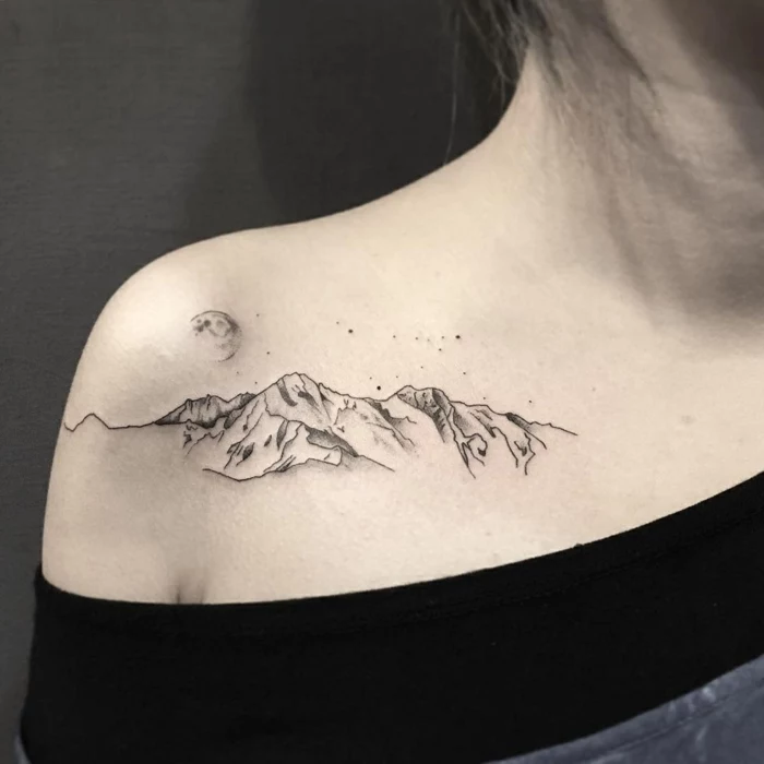 shoulder tattoo, mountain range with moon above it, mountain scene tattoo, woman wearing black blouse