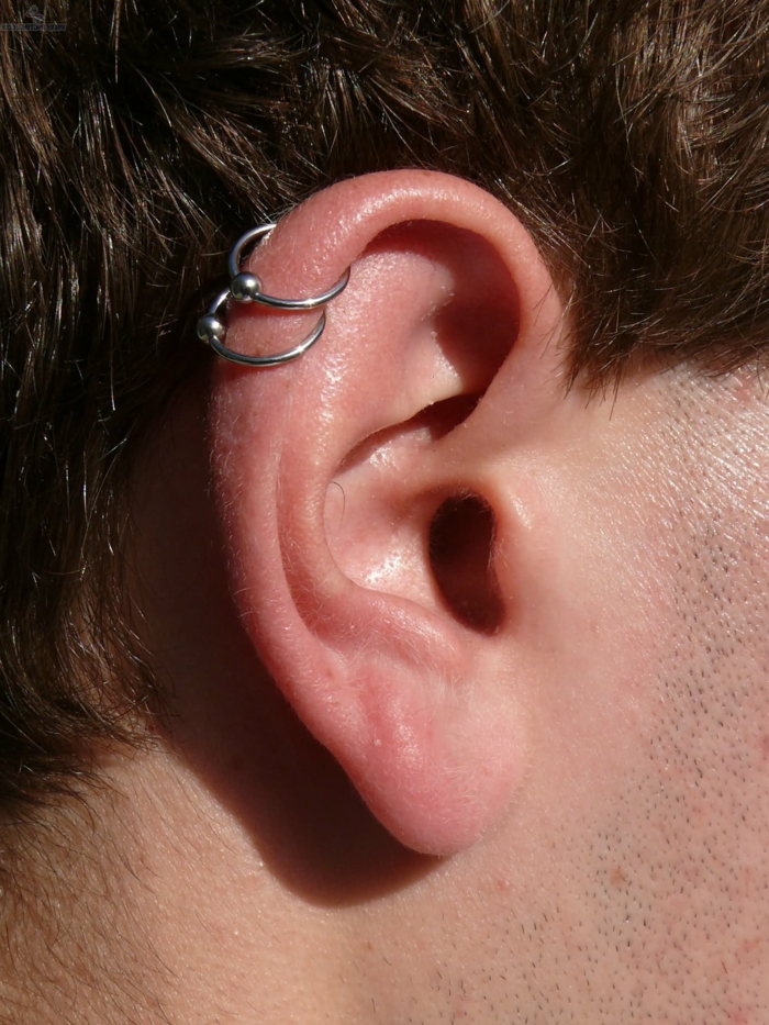 how long does a cartilage piercing take to heal, close up photo of an ear, wearing two silver ring earrings, man with brown hair
