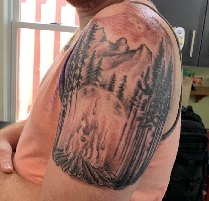 watercolor shoulder tattoo, mountain scene tattoo, camp fire burning between trees, mountain in the background