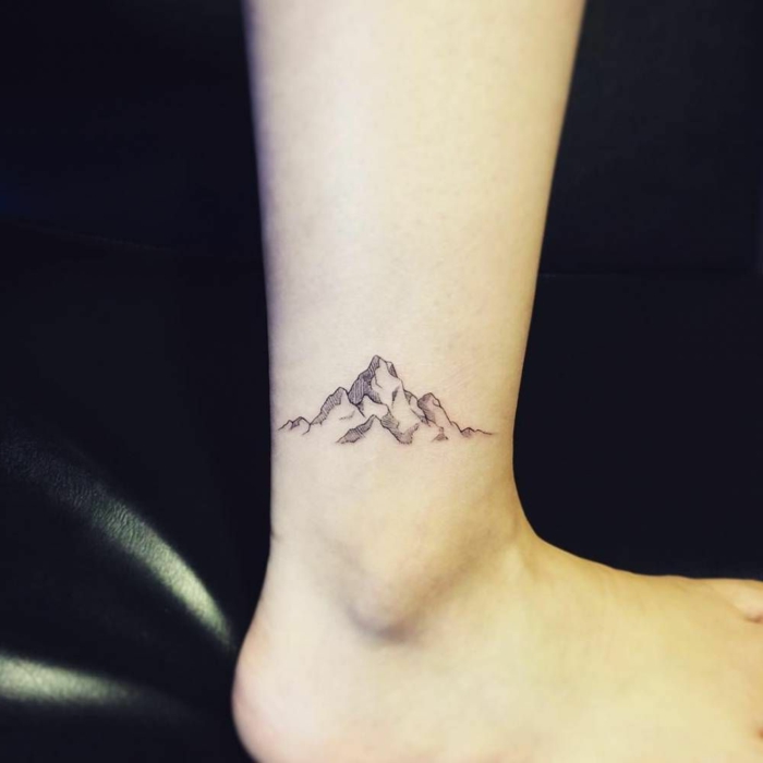 ankle tattoo, mountain scene tattoo, minimalist mountain range, black background