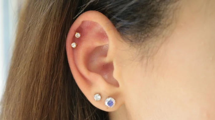 woman with brown hair, how long does a cartilage piercing take to heal, close up photo of an ear, earrings with rhinestones