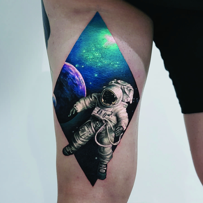 astronaut in space, traditional forearm tattoo, galaxy behind him, thigh tattoo