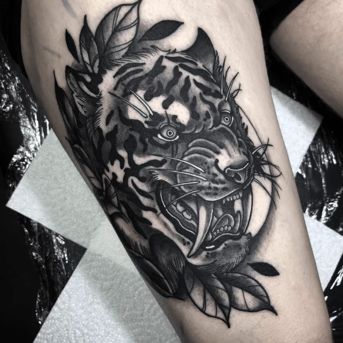 black and grey tattoo, thigh tattoo, growling tiger head with large teeth, traditional forearm tattoo