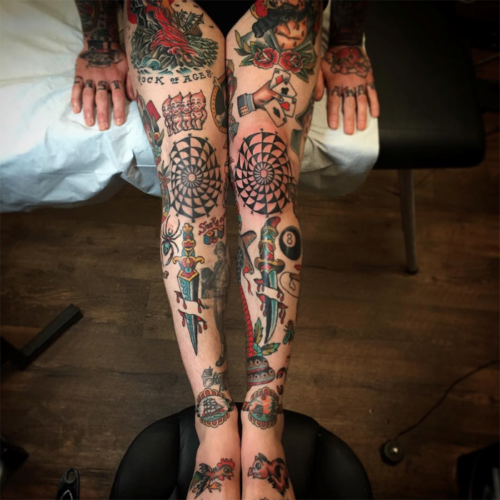 two legs covered with identical tattoos, leaning on black leather chair, traditional girl tattoo
