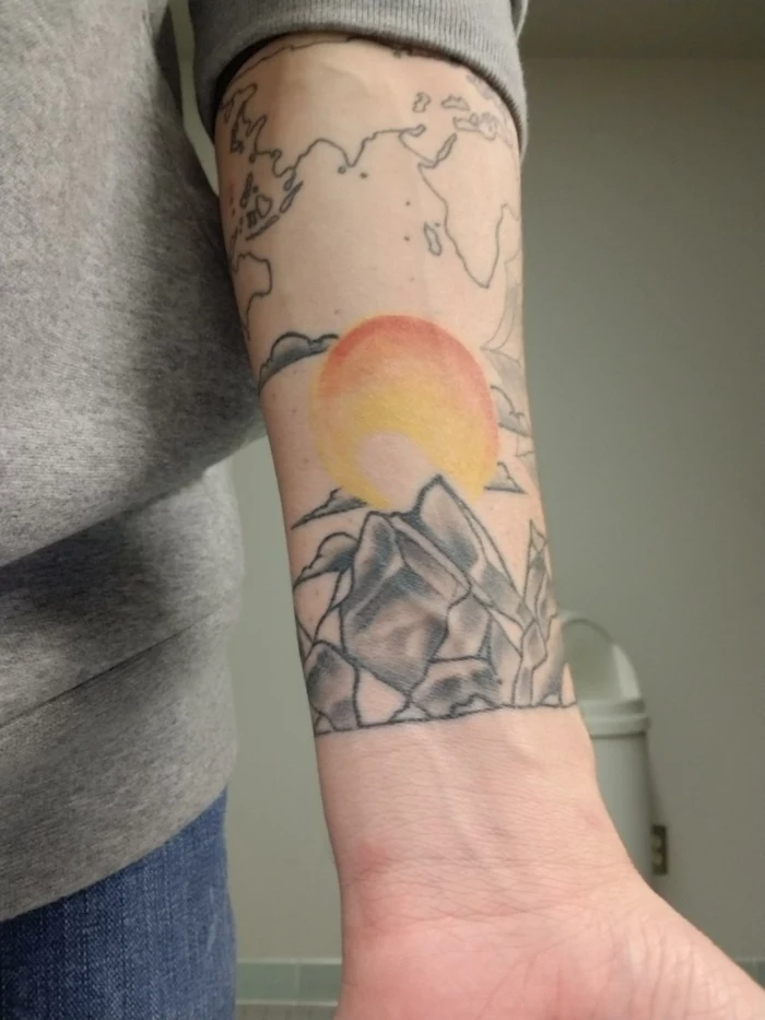 watercolor sun in yellow and orange, over a mountain range, mountain tattoo meaning, forearm tattoo