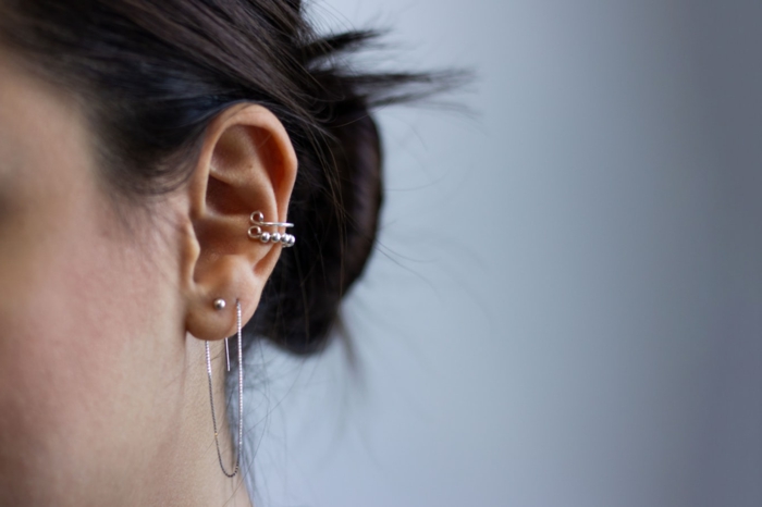 woman with black hair in low updo, how much is a cartilage piercing, wearing multiple earrings