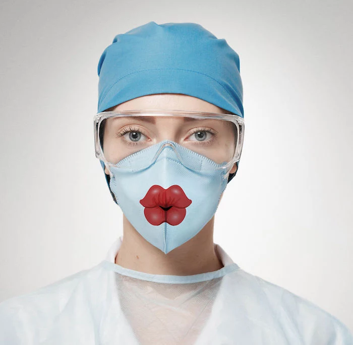 woman with blue eyes, wearing a face mask with lips prnted on it, diy breathing mask, surgical hat and goggles