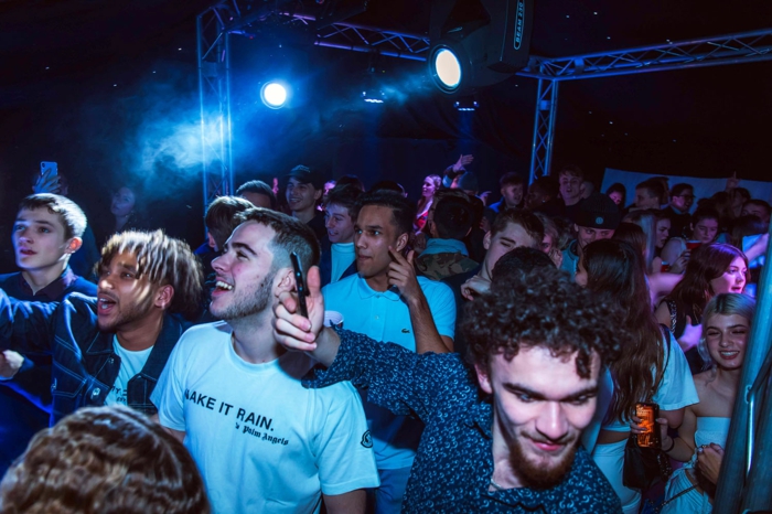 lots of people dancing in a club, lights above them, 18th birthday decorations, holding phones