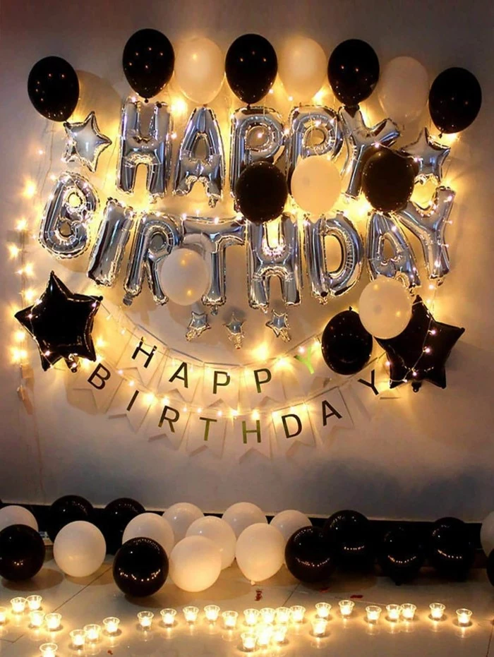 silver happy birthday balloons, surrounded by fairy lights, gifts for 18 year old boys, black and white balloons