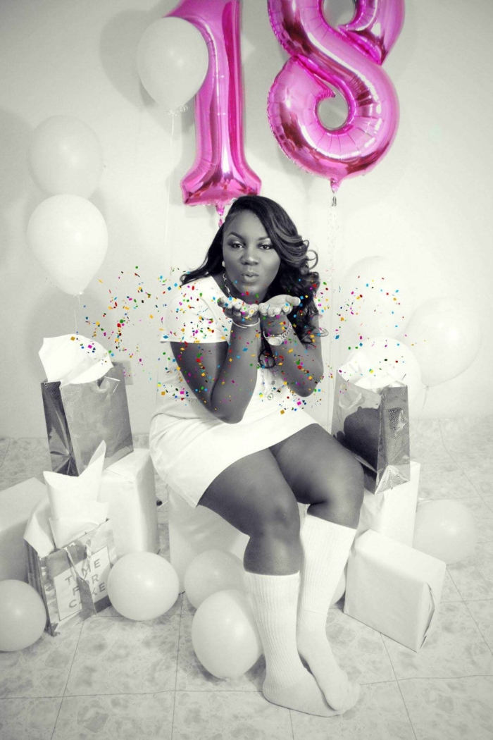 black and white photo, 18th birthday ideas, girl blowing confetti into the air, pink number 18 balloons