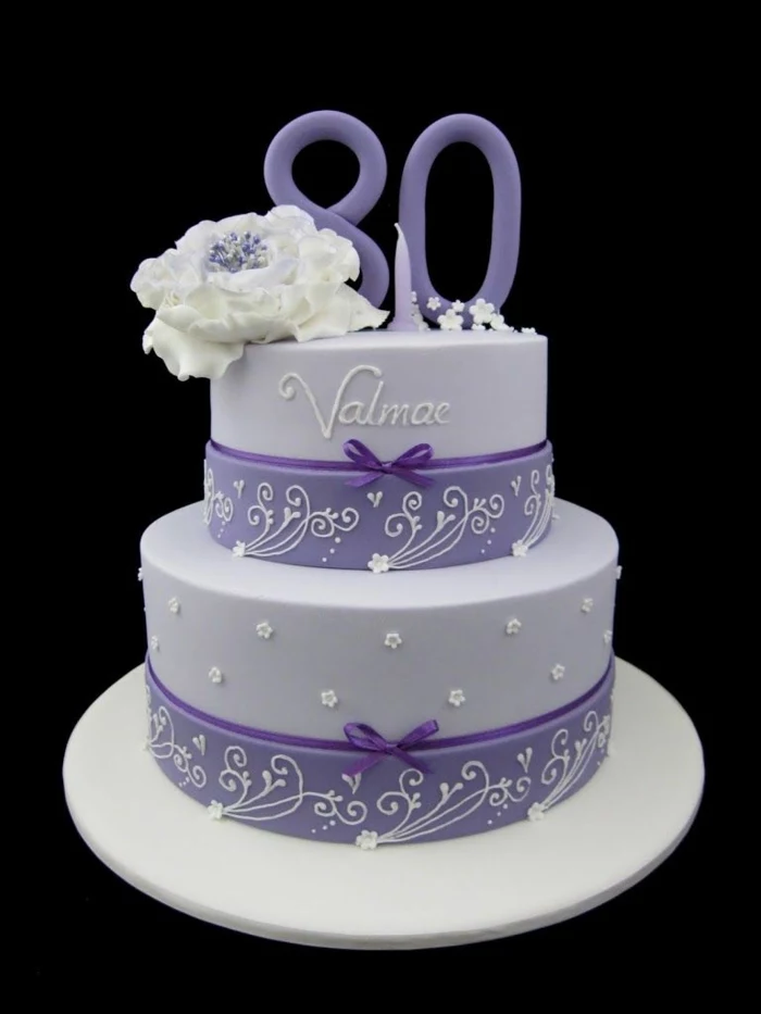 two tier cake, covered with purple fondant, 80th birthday ideas for mom, decoated with white flower