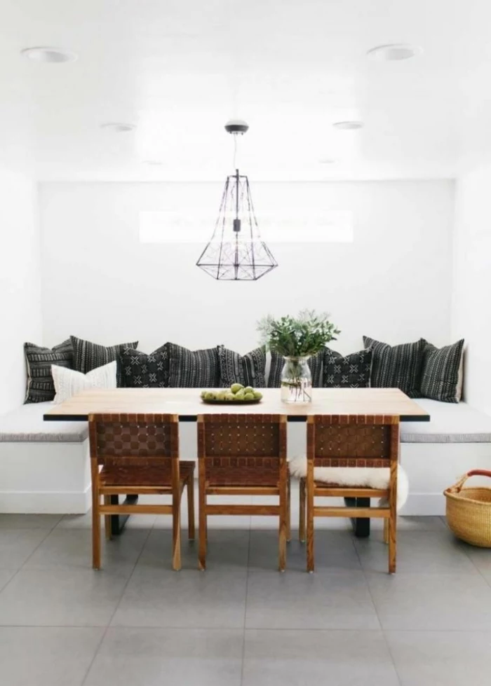 breakfast nook, black throw pillows, mid century kitchen, white table with wooden chairs, tiled floor