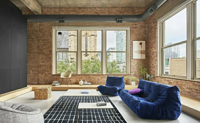 blue sofa and armchair, brick walls, decorations ideas for living room, white floor with black carpet