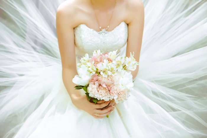 bride wearing a wedding dress, holding a bouquet, songs to walk down the aisle to, sittin down