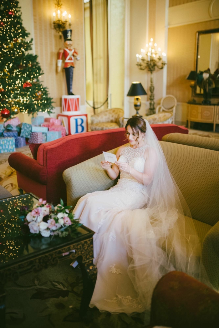 what to write in a wedding card, woman wearing wedding dress, sitting on a sofa, reading a card, christmas tree in the background