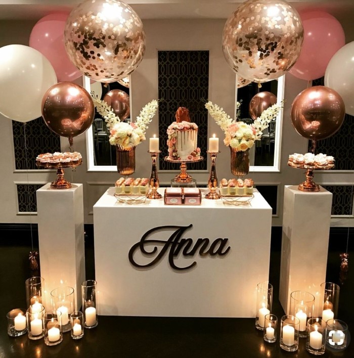 desserts table with white roses, surrounded by pink and rose gold balloons, candles on the floor, 18th birthday gifts