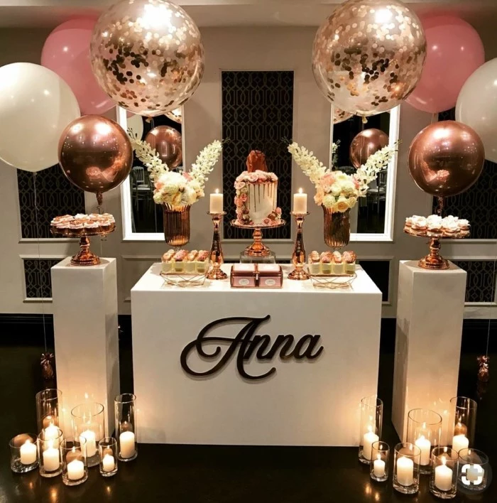 desserts table with white roses, surrounded by pink and rose gold balloons, candles on the floor, 18th birthday gifts