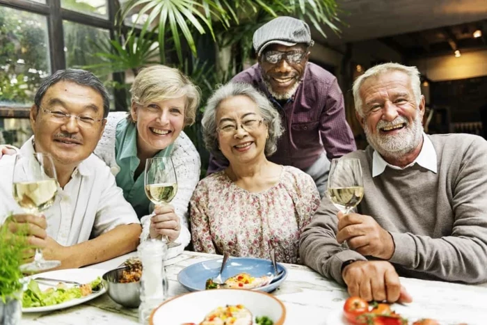 five people smiling, sitting at a table, holding wine glasses, 80th birthday party ideas