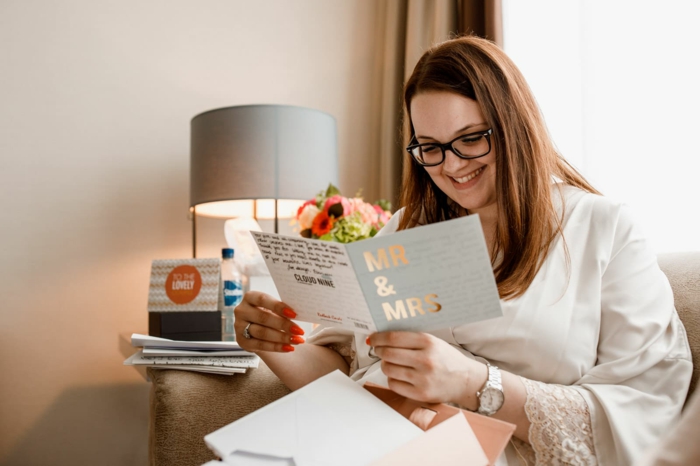 woman with light brown hair, wearing white silk robe, wedding congratulations message, reading a card