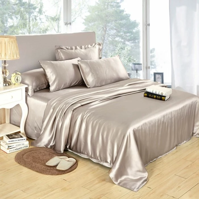 grey silk bed sheets, spread on large bed, anniversary gifts for her, white bed side table, books on the bed