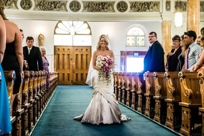 bride walking down the aisle alone, holding a large bouquet, wedding ceremony songs, photo from inside the chapel