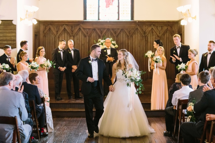 bride and groom walking down the aisle, wedding ceremony songs, wedding party in the background, photo from inside the chapel