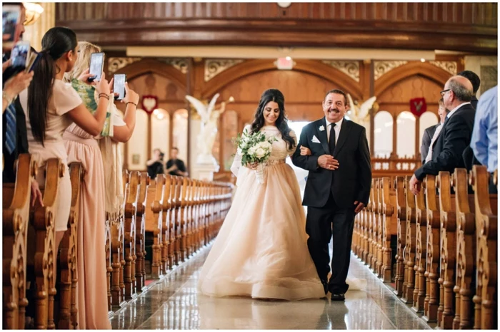 bride being walked down the aisle by her father, being photographed, wedding ceremony songs, photo from inside the chapel