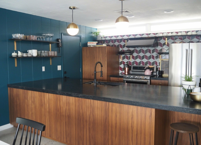 blue wall, wooden kitchen island, black granite countertops, mid century modern backsplash, tiled backsplash