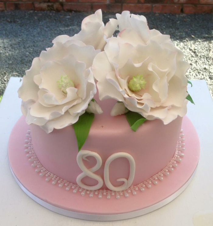 one tier cake, covered wih pink fondant, 80th birthday party decorations, decorated with white flowers